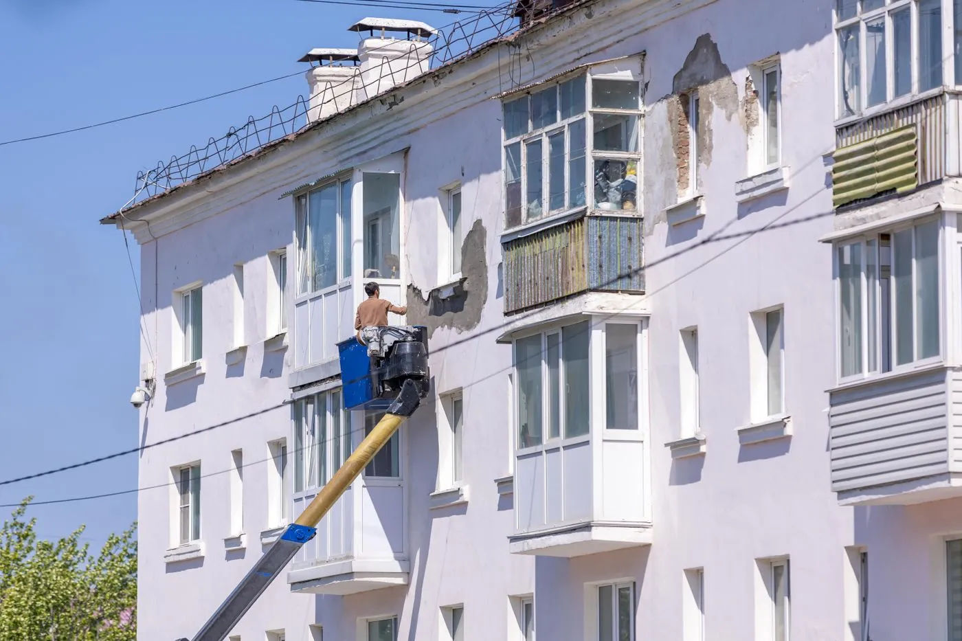 Operaio su cestello elevatore interviene sulla facciata di un edificio durante lavori di riqualificazione