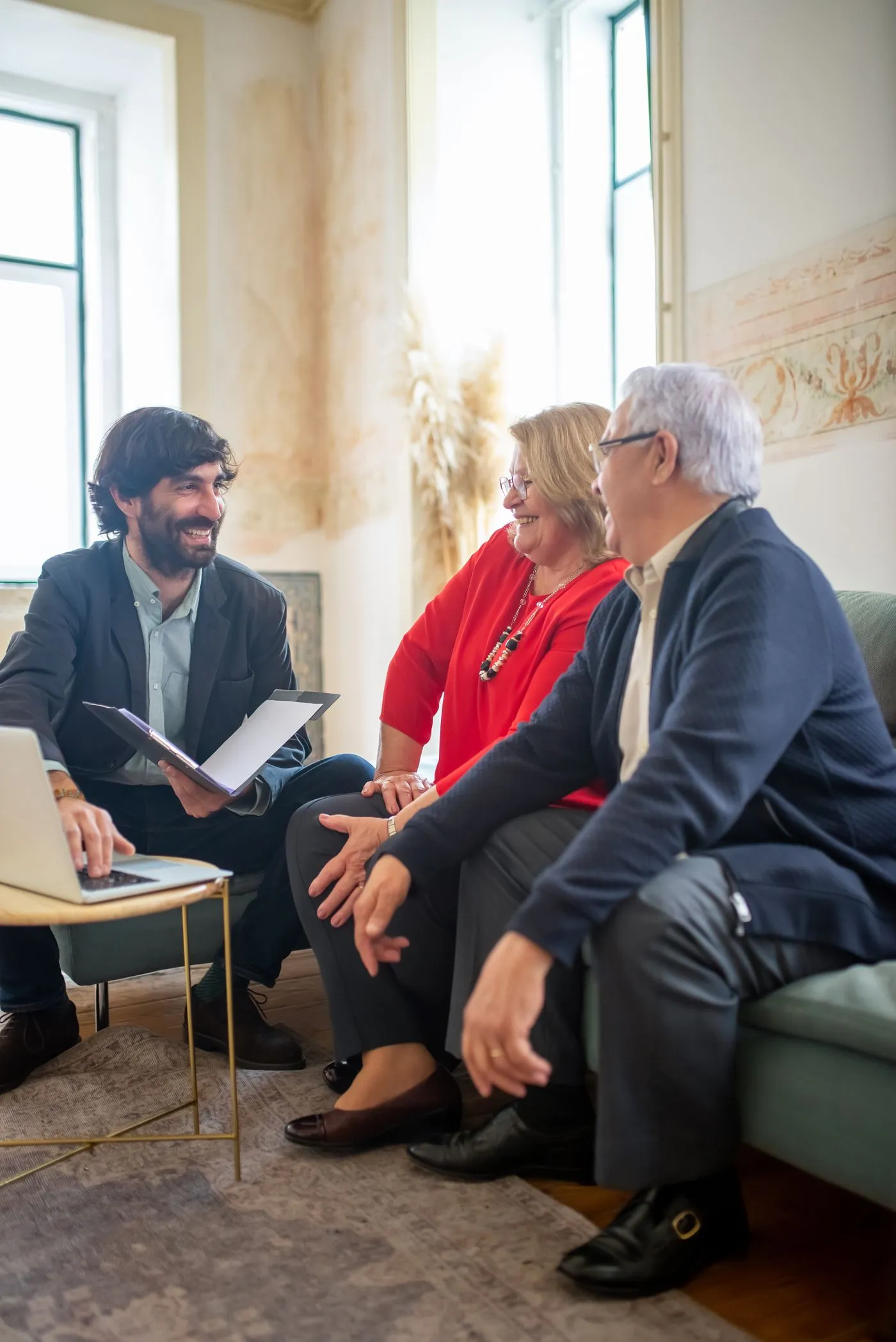 Consulente finanziario illustra le condizioni di un prestito a una coppia di clienti seduti sul divano